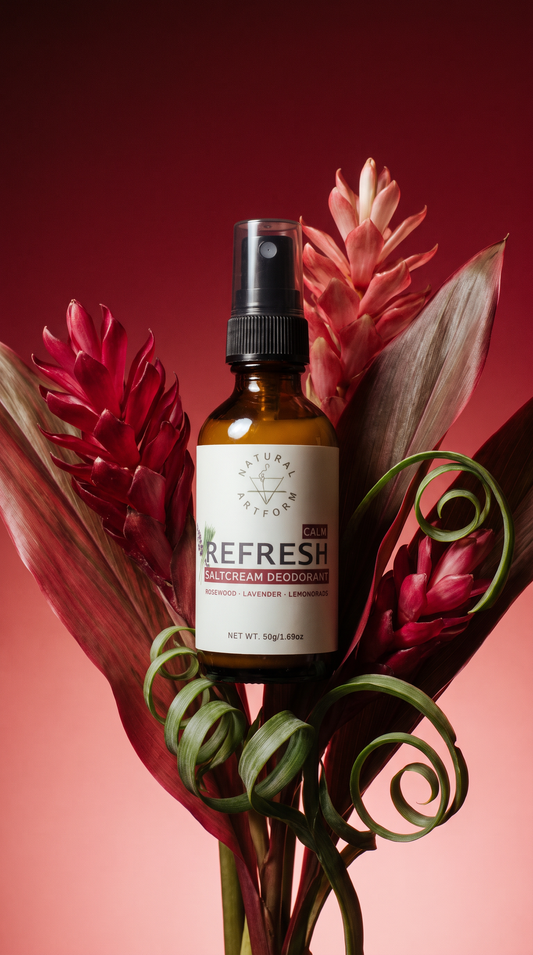 A bottle of Nature's Own 'Refresh' Salicylate Deodorant spray, styled with red and green tropical flowers against a dark red background.