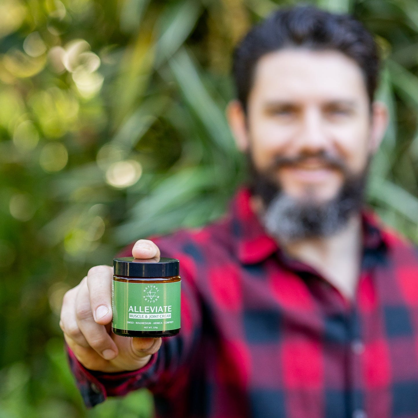 Man holding a jar labeled 'ALLEVIATE' in front of a blurred natural background